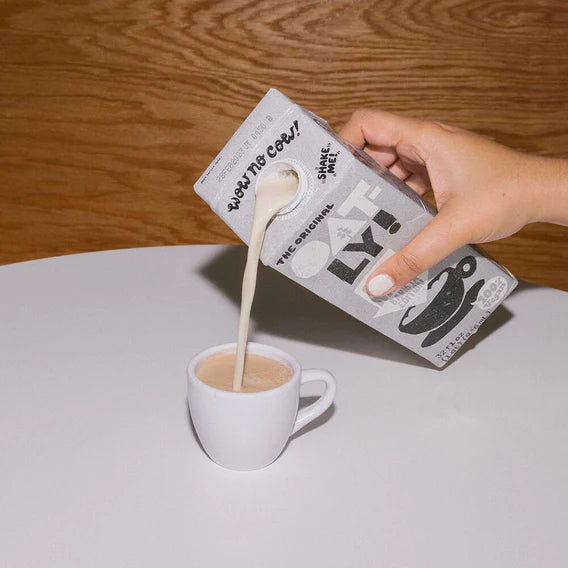 closeup of hand pouring oatly barista edition into a mug