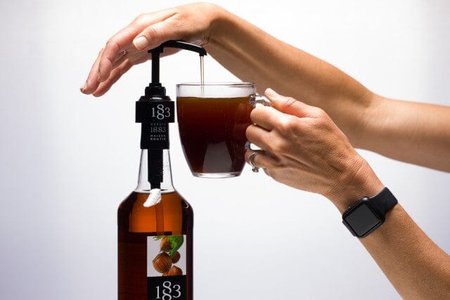 barista pumping syrup from routin 1883 coffee syrup pump into mug of coffee