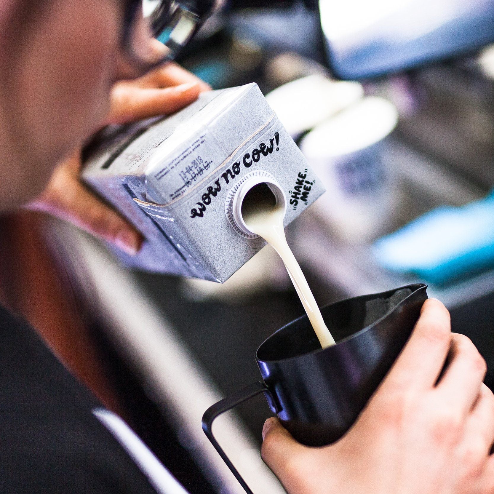 barista pouring oatly barista edition into cup